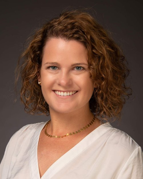Professional Headshot photo of Dr. Mia Nagawiecki in a white blouse against a dark grey background